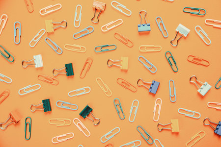 A lot of colorful paper clips lie on an orange background.の写真素材
