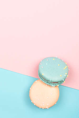Two colorful bright macaroons lie on a blue and pink background. Top viewの写真素材