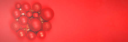 Red festive balls of different sizes lie on a red background. Monochrome. A wonderful banner for your decor.の写真素材