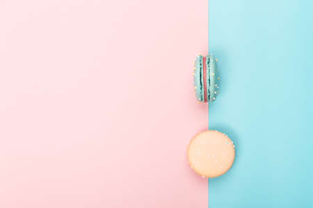 Two colorful bright macaroons lie on a blue and pink background. Top viewの写真素材