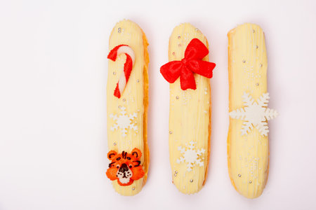 Festive eclairs with elements of 2022 on a white background. Decorated with a Christmas cane, a red...