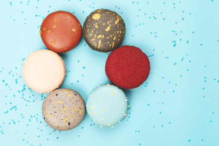 Six colorful bright macaroons lie on a blue background. Top viewの写真素材