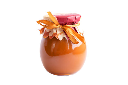 A beautiful gift jar with sweet jam tied with a shiny brown satin bow. Isolated.の写真素材