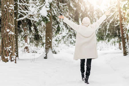 Set 2. A young girl in a white hat and an artificial fur coat enjoys a walk through a snowy forest in cold winterの写真素材