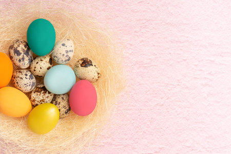 Colorful Easter eggs lie in a nest on a pink background. Easter holiday concept, flat lay.