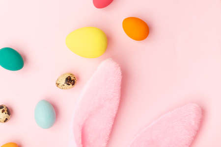 Colorful Easter eggs and bunny toy ears lie on a pink background. The concept of the Easter holiday, flat lay.の写真素材