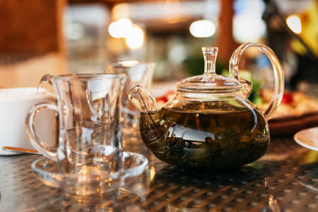 Green leaf tea is brewed in a teapot. There is a tea pair on the table.の写真素材