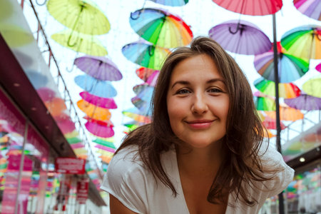 Summer portrait of a beautiful smiling girl on a background of colorful umbrellas.