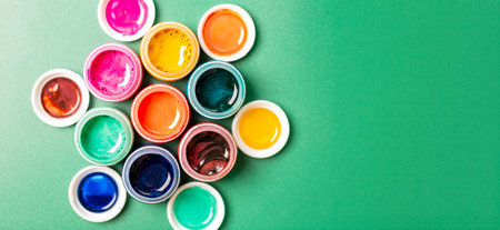 Beautiful, bright, mother-of-pearl, multicolored open cans of paint on a bright green background. view from above. The concept of creativity.の写真素材