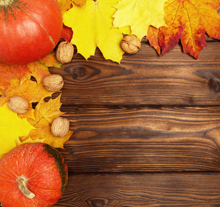 Autumn background. Yellow, orange, red fallen autumn leaves on a beautiful, brown, textured wooden background.の写真素材