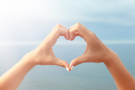 A heart from the hands on the background of the sea. Concept: love of travel.