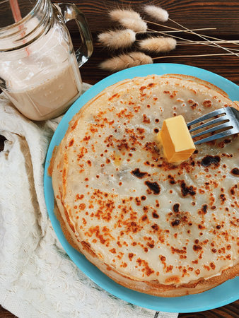 Freshly baked pancakes are smeared with butter.