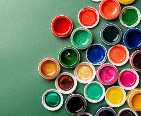 Beautiful, bright, mother-of-pearl, multicolored open cans of paint on a green background. View from above. The concept of creativity.の写真素材