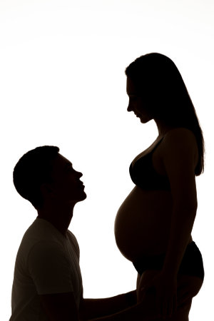 Dark silhouette of a man and a pregnant woman on a white background.の写真素材