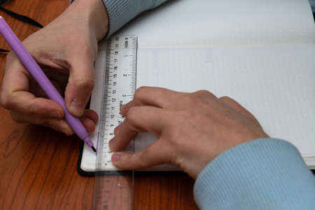 Girl's hands making a calendar on its bullet journal in spanishの写真素材