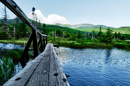 Old wooden bridge over a river into the wilderness of the appalachian trail and mountains with forest and woodland in the unsharp backgroundの写真素材