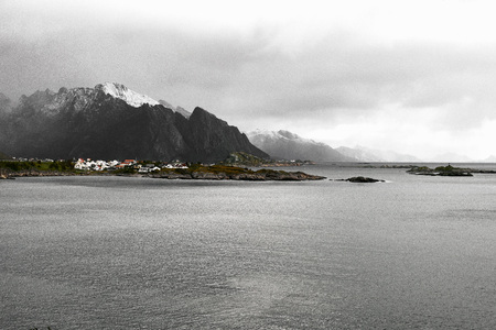 Panoramic view of the norwegian coast and a village in front of a snowcapped mountain range during winter on Lofoten Islands in Norway.の写真素材