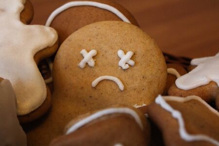 Homemade gingerbread men in the woven basket on the wooden table. Depressed christmas cookie with sad face covered with icing. New Year pastry in the shape of stars and men. Winter backgroundの写真素材