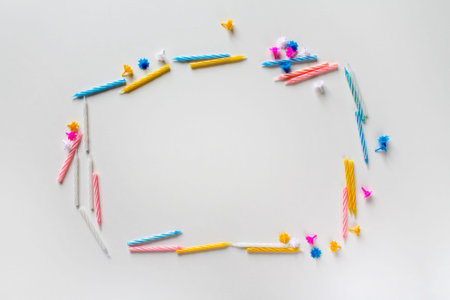 Text frame made of bright colorful birthday candles on white background. Yellow, pink, blue and...