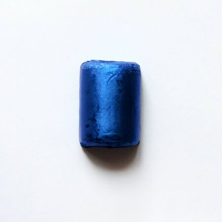 Chocolate candy wrapped in blue foil isolated on white surface. Object for greeting card, poster or invitation. Backdrop or backgroundの写真素材