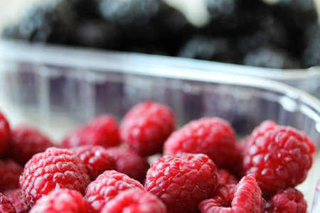 Background with fresh berries in plastic boxes closeup. Blackberry and raspberry macro photography....