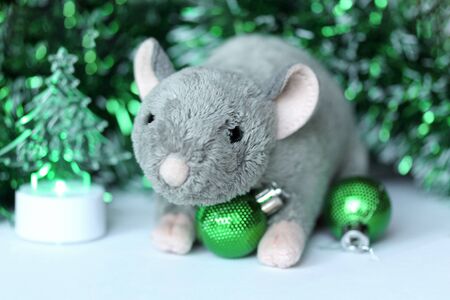 Cute rat or mouse soft toy with green ornaments and tinsel. Chinese New Year symbol. Festive background with copy space for text. Poster or greeting card templateの写真素材