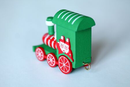 Green festive wooden train locomotive or railway engine on white background. Christmas and New Year toy with figures of waving santa or gnome. Greeting card, poster templateの写真素材