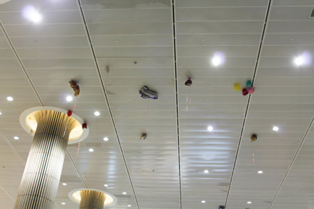Air balloons of different shapes under the ceiling at the airport. Airplane, teddy bear and colorful...