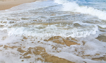 Sea foam on the sandy beach at Bat Yam, Israel. Waves on the blue stormy sea. Mediterranean...