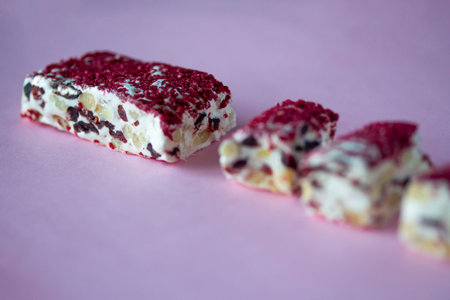 Torrone or nougat bar with nuts and red dried berries. Traditional italian dessert close up on pink...