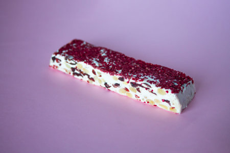 Torrone or nougat bar with nuts and red dried berries. Traditional italian dessert close up on pink...