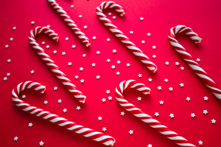 Christmas background with candy canes. Red sweet sticks with small stars. Flat lay, overhead view....