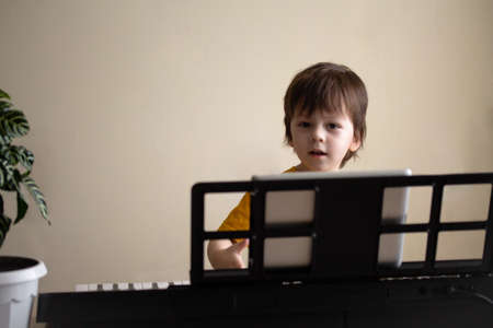 A boy playing the synthesizer. Toddler learning how to play piano. Childs hands on the keyboard. Early development and education conceptの写真素材