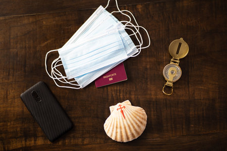A passport, some surgical masks, a compass, a smartphone and a shell with a red cross painted with...