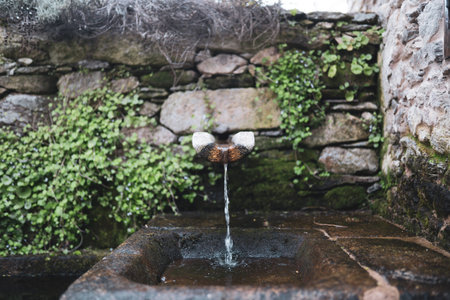 Ancient stone fountain, with water and a stone wallの写真素材