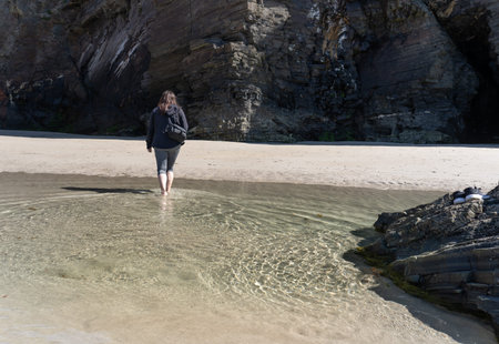 Woman walking in the water at the beach on a sunny day, lifestyle, copy space.