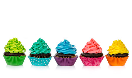 Chocolate cupcakes in a row with colorful icing on a white background.の写真素材
