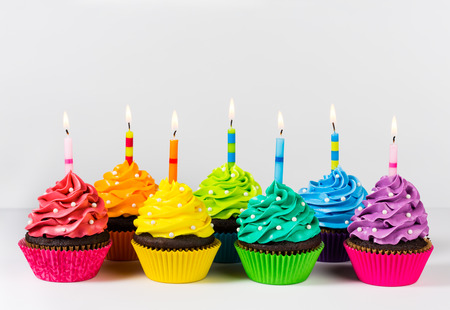 Rows of colorful cup cakes decorated with birthday candles and sprinkles.の写真素材