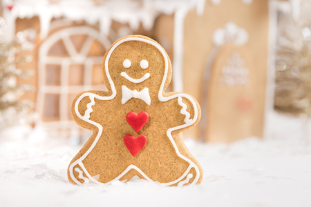 Gingerbread man cookie standing in front of a gingerbread house.の写真素材