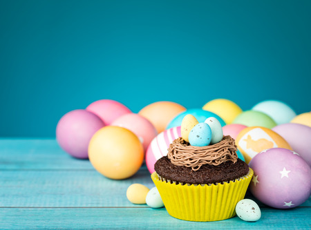 Colorful Easter Eggs and cupcake with nest on a blue background.の写真素材