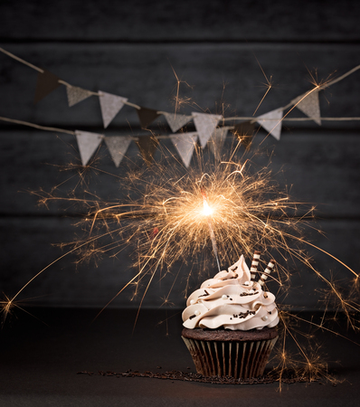 Chocolate cupcake with lit sparkler on a dark background.の写真素材