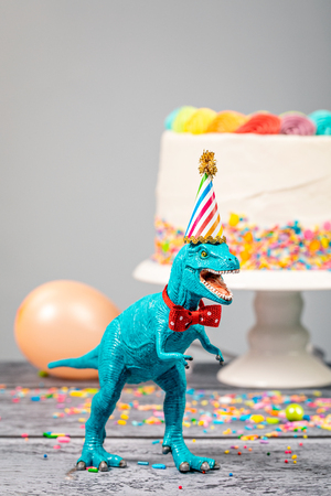 Toy dinosaur at a Birthday party wearing a hat and bow tie.の写真素材