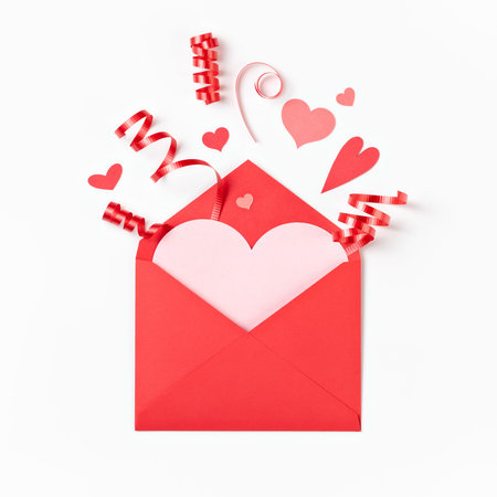 Red envelope with Valentine hearts and ribbon popping out on a white