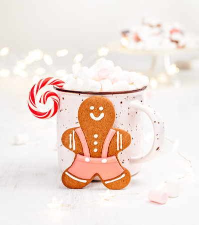 Gingerbread Man Christmas cookie with a mug of hot chocolate, marshmallows and a candycane over a...