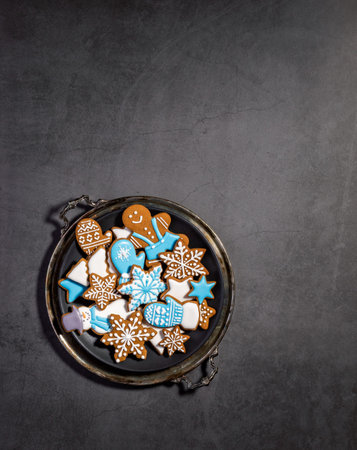 Decorated Blue and White iced gingerbread Christmas cookies on rustic platter. Grey background. Top...