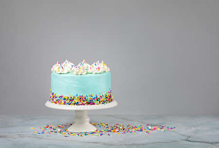 Blue Birthday Cake with colorful sprinkles over a light grey background.の写真素材