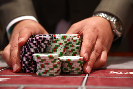 Player at gambling table pusing large stack of chipsの写真素材