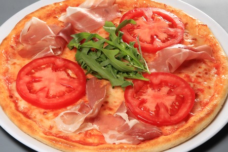 Pizza with prosciutto, tomatoes and arugula , closeupの写真素材