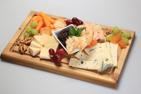 Mix cheese on a oard with some fruits on the sideの写真素材