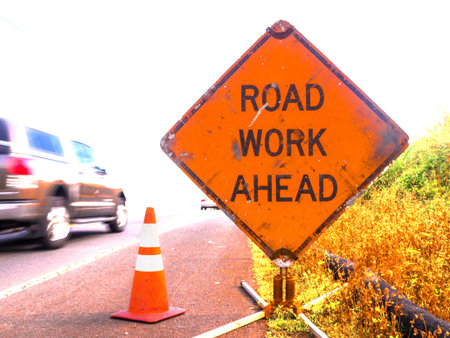 A sign reading Road Work Ahead is passes by a fast car